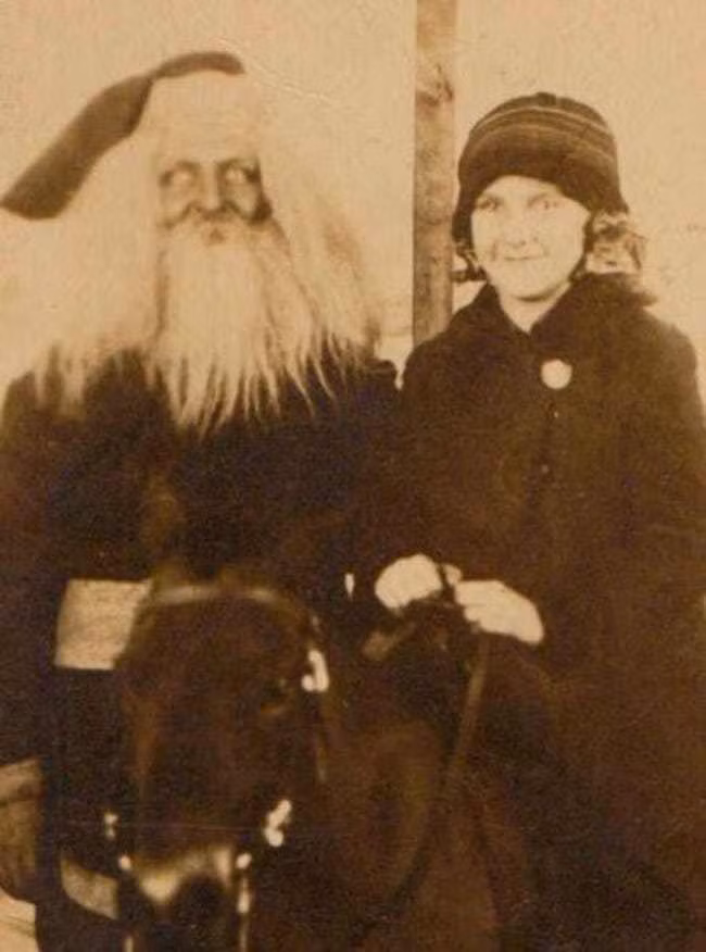 Một cô bé cưỡi ngựa đứng cạnh ông già Noel.