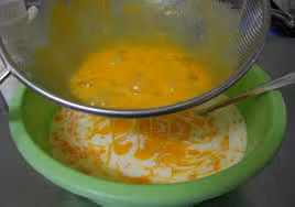 Tiếp đó, dùng rây để lọc hỗn hợp trứng sữa tươi một lượt nữa để hỗn hợp hòa đều và mịn hơn. Lọc trứng sữa xong bạn cho tiếp 2 ống vani vào hỗn hợp và khuấy nhẹ tay