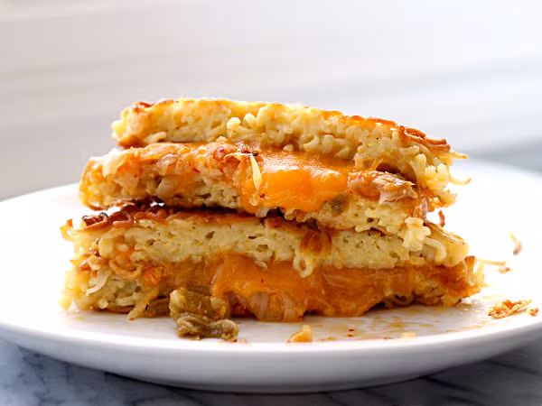 Bạn có thể chế biến sandwich mỳ theo cách sau: Đầu tiên chần mỳ nở vừa tới, để ráo nước. Đập trứng vào chiếc bát con, cho vào trộn đều cùng mỳ. Lấy chiếc hộp hình vuông hoặc hình chữ nhật, phết bơ và dầu ăn kín thành hộp, cho toàn bộ số mỳ trộn trứng vào hộp và nén xuống tạo thành hình vuông. Cho hộp nén mì vào tủ lạnh khoảng 20 phút.