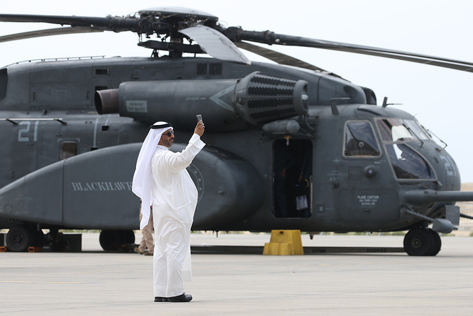 Một người đàn ông đang đứng chụp ảnh bên cạnh trực thăng UH-60 Black Hawk, phiên bản thiết kế dành cho lực lượng đặc nhiệm. Ảnh: TASS.