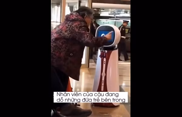 Có vẻ như bà lão không hài lòng về phong cách phục vụ của nhân viên tại ngân hàng này là robot TuTu. Trong khi những nhân viên khác đang cố gắng dỗ dành những đứa trẻ bên trong thì TuTu lại chỉ biết đứng ngoài để "kiếm tiền".