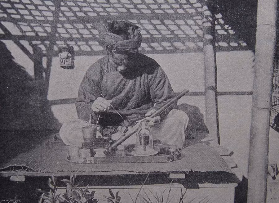 Người đàn ông sửa soạn tẩu hút thuốc phiện.