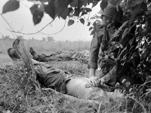 Quân y Mỹ đang sơ cứu cho một người lính Mỹ có vẻ như đã bất tỉnh, bên cạnh anh ta là một người khác cũng đang nằm trên đất chờ để được sơ tán. Nguồn ảnh: Thearchive.