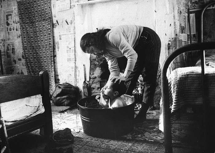 Căn nhà chật chội khiến người phụ nữ này phải tắm cho một cậu bé ngay trong một chiếc chậu được đặt trong phòng ngủ.