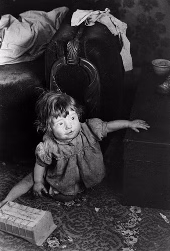 Một em bé mặt mũi lấm lem đang chơi đùa trong một ngôi nhà bừa bộn và chật chội ở vùng thung lũng Appalachia.