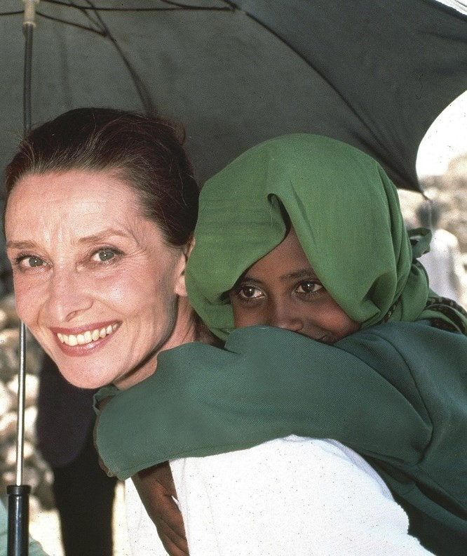  9. Audrey Hepburn và một cô gái Ethiopia, 1988: Nhiều người nhớ đến Audrey Hepburn qua hình ảnh một nữ diễn viên và một người phụ nữ thanh lịch nhưng rất ít ai biết rằng bà cũng là một Đại sứ thiện chí của UNICEF. Bà đảm nhận vị trí này khi hoàn thành sự nghiệp diễn xuất và dành phần còn lại của cuộc đời để cải thiện chất lượng cuộc sống cho trẻ em từ những nước nghèo nhất. Bà đã đến thăm một trại trẻ mồ côi ở Ethiopia, mang thực phẩm cứu trợ của UNICEF đến cho 500 trẻ em bị đói tại đây. Bà đến Thổ Nhĩ Kỳ trong một chiến dịch tiêm chủng. Nhờ nỗ lực của bà, các trường học mới được xây dựng và các cộng đồng miền núi ở Nam Mỹ đã nhận được hệ thống nước sạch. Chuyến thăm cuối cùng của bà tới Somalia chỉ cách 4 tháng trước khi qua đời vì bệnh ung thư vào năm 1992.