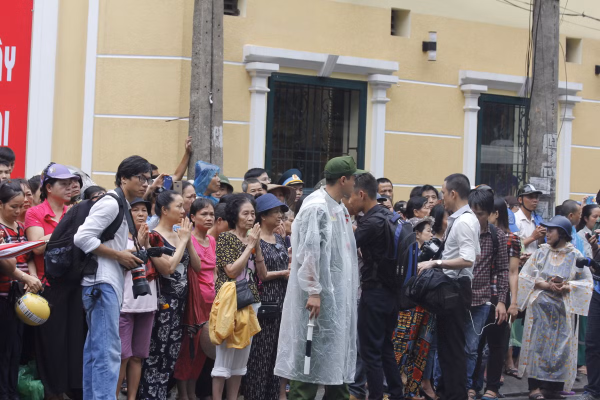 Hàng trăm người dân đứng chờ chào vĩnh biệt vong hồn 9 liệt sĩ trong mưa.