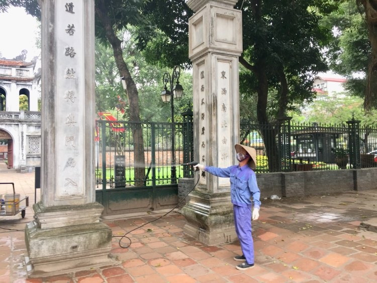 Hình ảnh nhân viên vệ sinh phun thuốc khử trùng tại cổng di tích Văn Miếu - Quốc Tử Giám.
