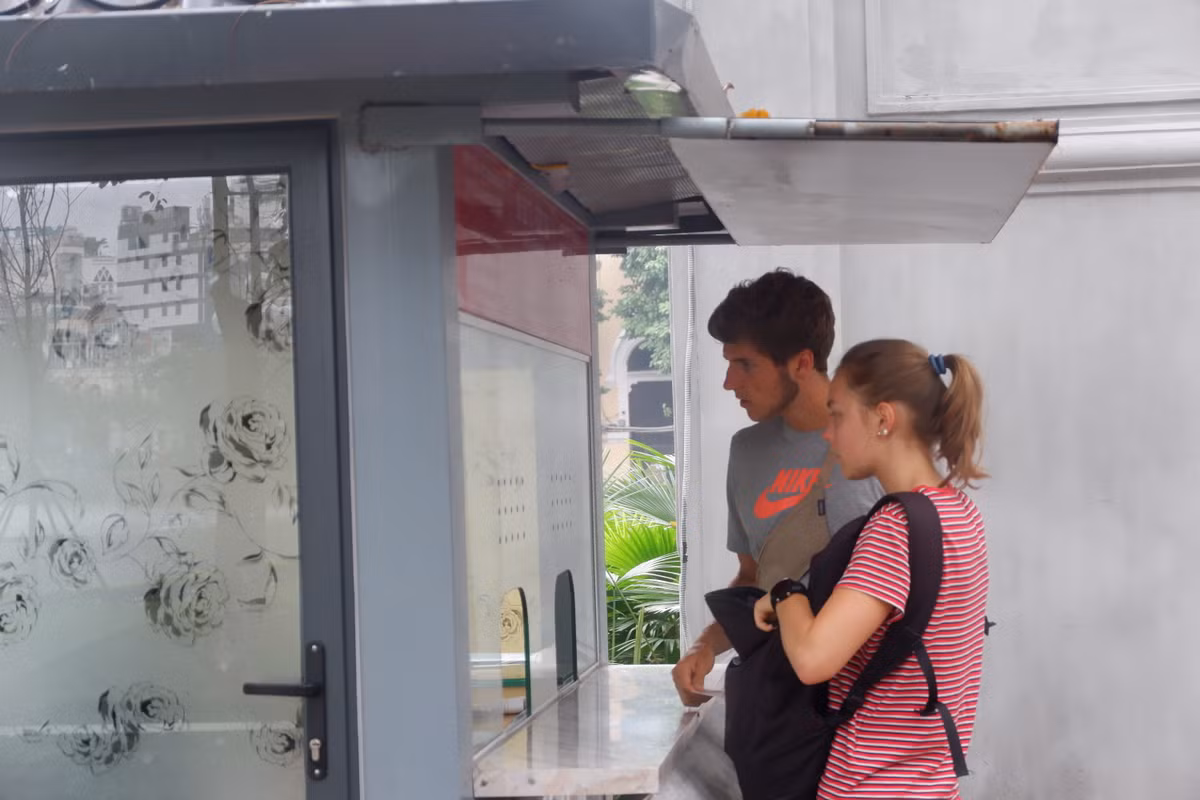 Hình ảnh du khách không đeo khẩu trang khi mua vé vào thăm quan di tích Đền Ngọc Sơn dù tiếp xúc gần với nhân viên bán vé.