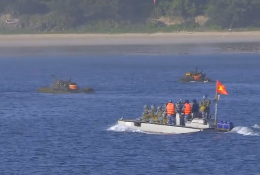 Các xe tăng PT-76B bắt đầu tiến vào bờ biển “đang bị quân địch chiếm giữ”, phía sau là đội thuyền chở quân đổ bộ tiếp ứng.