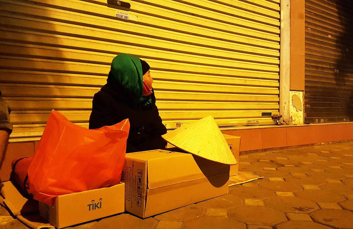 Một cụ bà co ro bên những thùng xốp dùng để chắn gió.