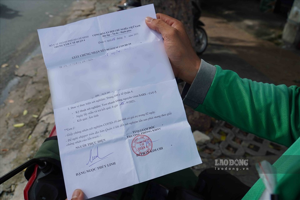 "Tôi vừa hoàn thành xong đơn giao hàng liên quận, từ quận 1 sang quận Tân Phú. Khi đến các chốt, tôi xuất trình đầy đủ giấy tờ từ giấy đi đường, giấy xét nghiệm âm tính, thẻ shipper và đeo băng tay nhận diện để lực lượng chức năng nhận diện và cho phép chạy đơn liên quận" - anh Ngô Xuân Phúc (shipper) cho hay.