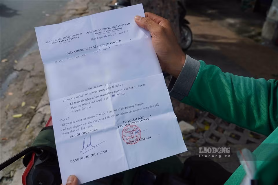 "Tôi vừa hoàn thành xong đơn giao hàng liên quận, từ quận 1 sang quận Tân Phú. Khi đến các chốt, tôi xuất trình đầy đủ giấy tờ từ giấy đi đường, giấy xét nghiệm âm tính, thẻ shipper và đeo băng tay nhận diện để lực lượng chức năng nhận diện và cho phép chạy đơn liên quận" - anh Ngô Xuân Phúc (shipper) cho hay.