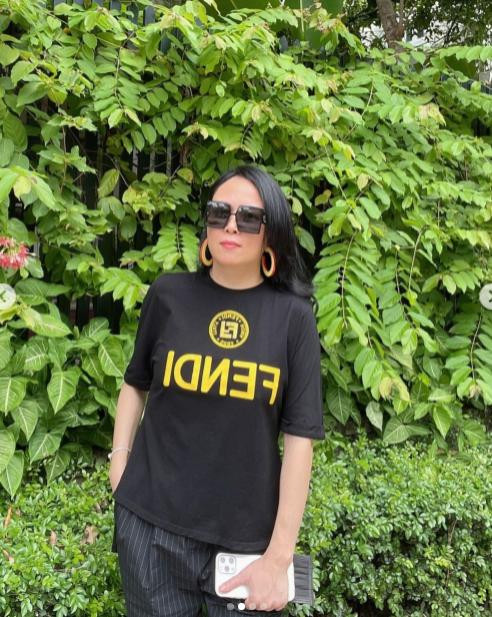 Ở nhà mùa dịch, Phượng Chanel chia sẻ trên trang cá nhân loạt ảnh ăn diện xinh đẹp chụp trước khuôn viên nhà. Nữ doanh nhân chọn cho mình chiếc áo phông Fendi đắt đỏ mix ton sur ton với quần kẻ sọc. Để vẻ ngoài trở nên bớt nhàm chán, nữ doanh nhân khéo léo phối thêm kính râm và đeo một đôi hoa tai bản to mang màu sắc nổi bật.