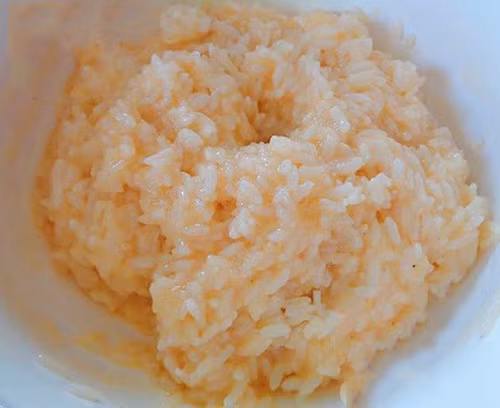 Cách làm pizza cơm nguội như sau: Bước 1: Cho trứng gà và một chút muối vào tô cơm nguội, trộn đều lên trước.