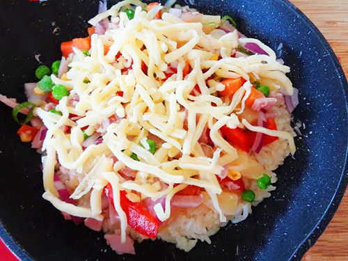 Bước 4: Cho vào chảo một lớp cơm mỏng, dàn đều ra rồi cho nguyên liệu đã trộn ở bước 2 rải đều lên bề mặt trên của cơm. Sau đó rắc thêm một lớp phô mai ngoài cùng.