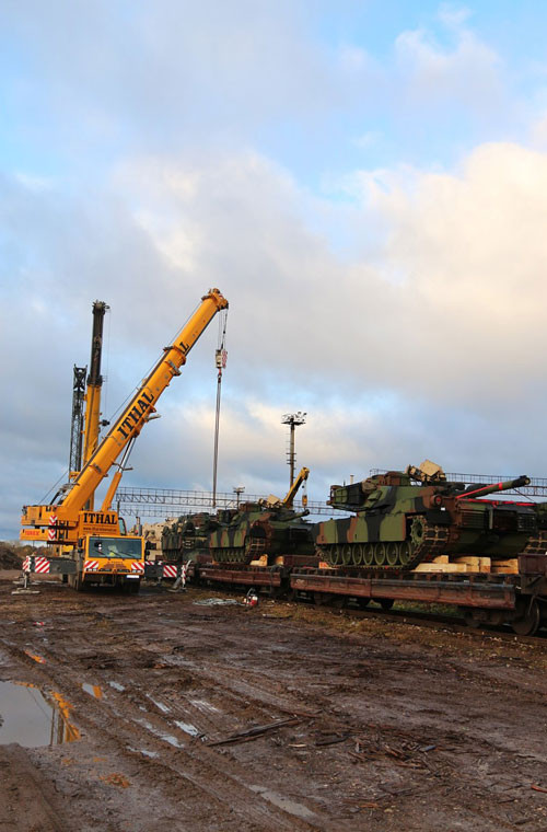 Hệ thống cần cẩu đang đưa xe tăng Abrams khỏi tàu hàng.