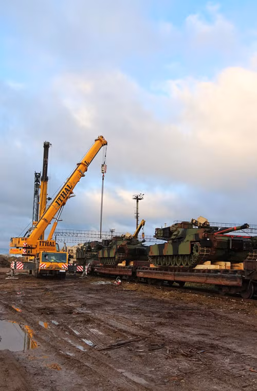 Hệ thống cần cẩu đang đưa xe tăng Abrams khỏi tàu hàng.