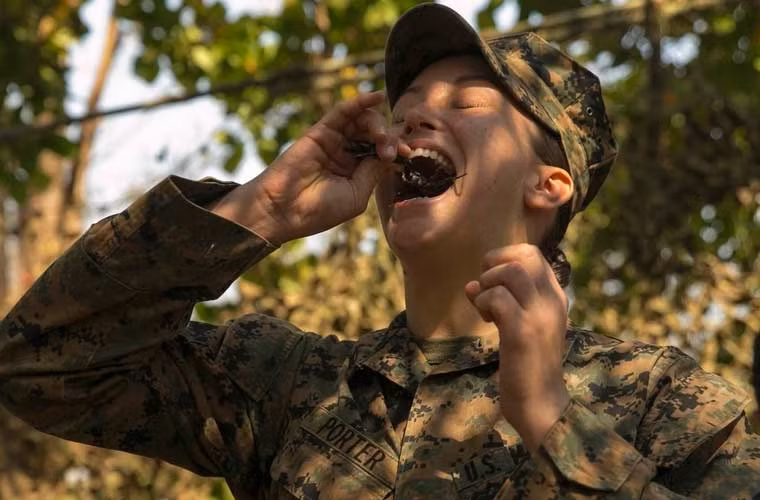 Nữ binh sĩ nhắm mắt ăn con bọ cạp sống nguyên trong cuộc tập trận Hổ mang Vàng 2015.