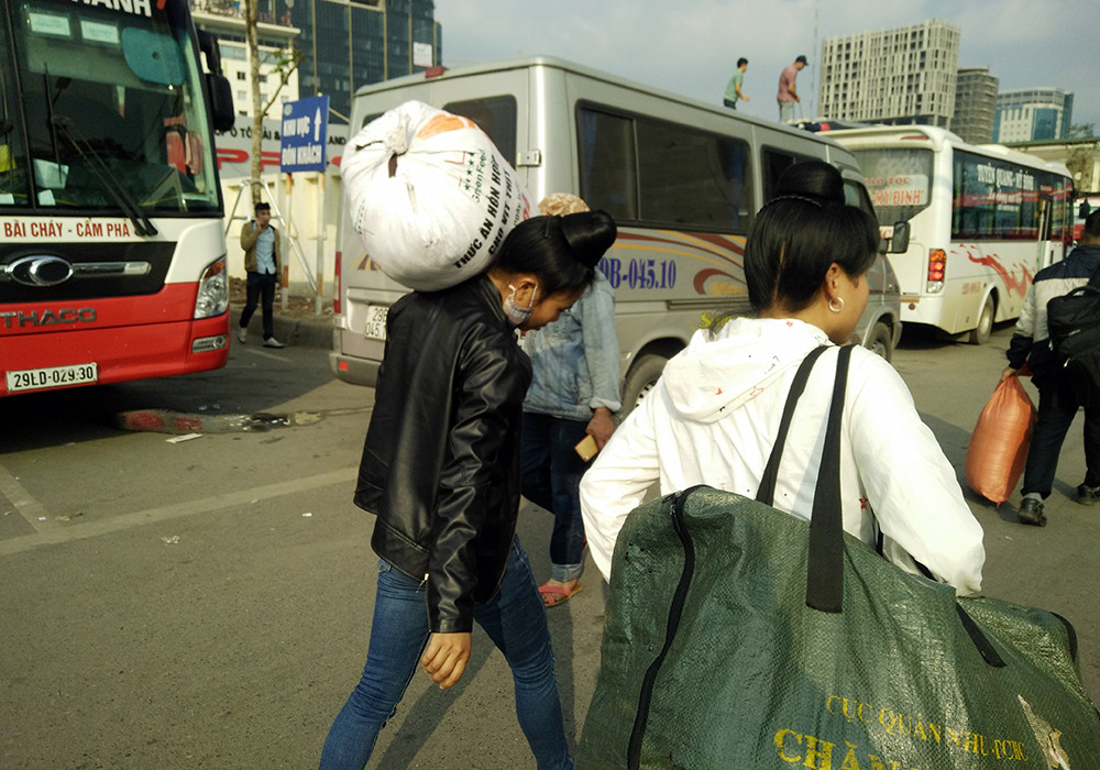 Hai người phụ nữ vác nhiều bao tải, đồ đạc về quê.