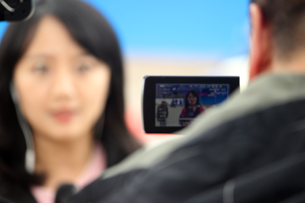 Nữ phóng viên tác nghiệp trực tiếp cùng với các trang thiết bị ghi hình hiện đại để truyền tải các thông tin quan trọng của sự kiện này.