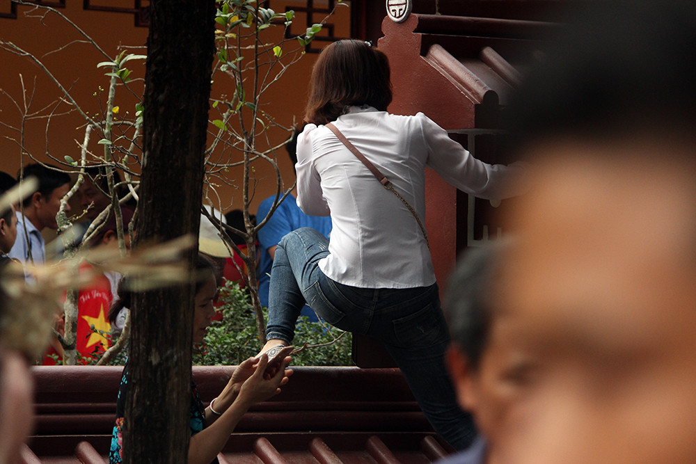 Có cả những du khách nữ leo tường chùa để đi.