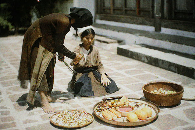 Hai người phụ nữ bên cạnh những nông sản như ngô, chuối... do gia đình tự trồng.