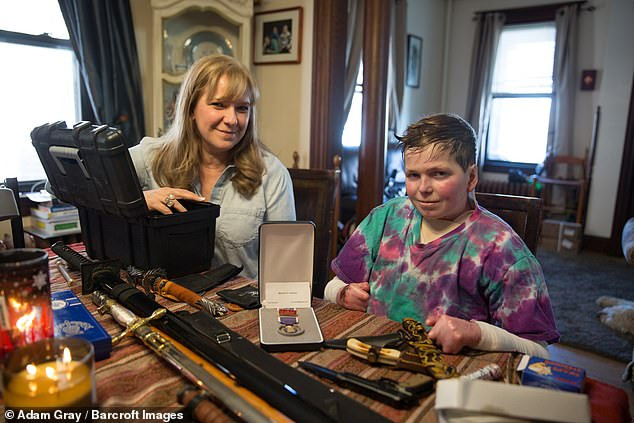 EB dù gây đau đớn cho John nhưng không thể cản trở cậu sống tích cực với nhiều sở thích. Trong hình là John chụp hình với bộ sưu tập dao của mình và tặng trái tim Purple Heart cho mẹ.