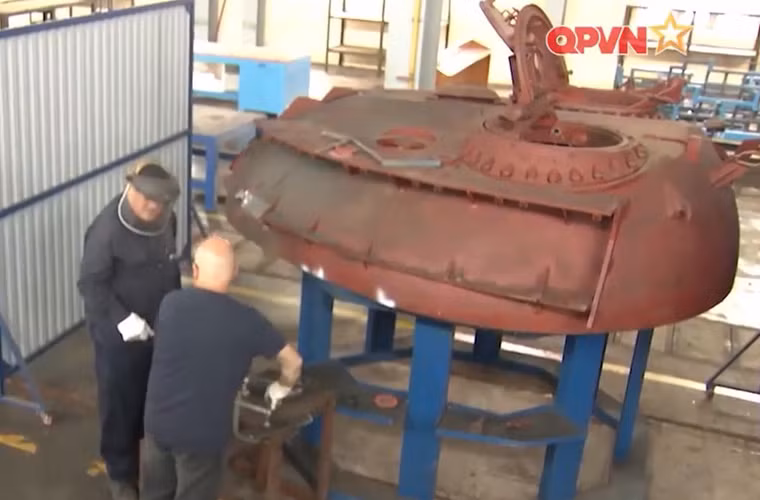 Việc nâng cấp xe tăng T-54B có sự tham gia của một số chuyên gia nước ngoài. Trong ảnh, có thể thấy hai chuyên gia nước ngoài đứng cạnh tháp pháo T-54B đã được làm lại để lắp thêm các khối giáp tăng cường. Nguồn ảnh: Kênh Quốc phòng Việt Nam