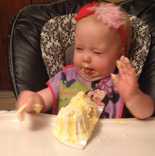 Bé gái ăn bánh bằng tay với vụn bánh rơi vãi khắp nơi.