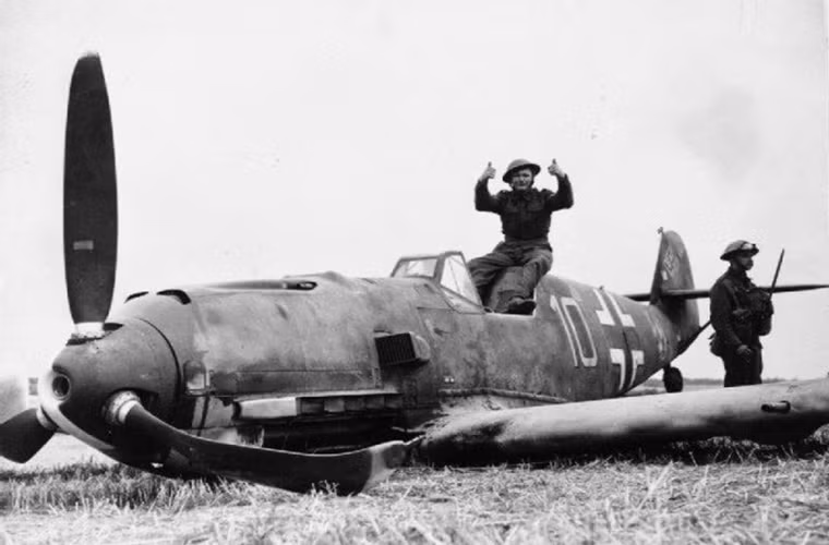 Binh sĩ Anh ra hiệu chiến thắng bên cạnh xác của một chiếc Messerschmitt Bf 109E bị bắn hạ ở đông Langdon, Kent. Nguồn ảnh: War History.