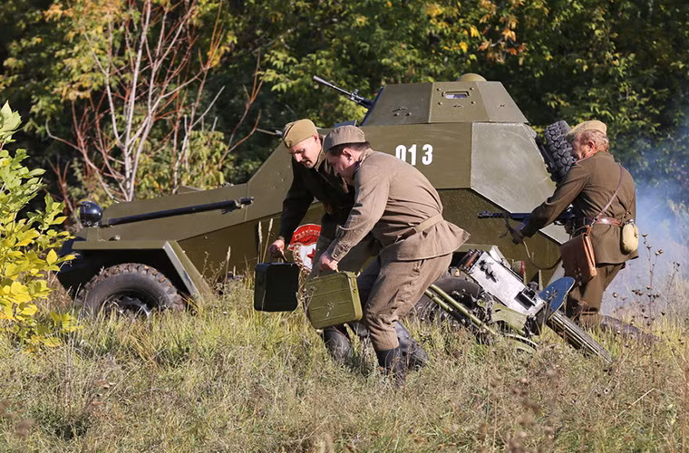 Hai binh sĩ Hồng quân kéo theo khẩu súng máy Maxim 1910 của mình ra tuyến đầu của chiến trường dưới sự hổ trợ của xe bọc thép hạng nhẹ BA-64.