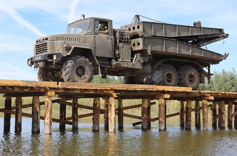 Theo Arms-Expo, cầu cơ giới TMM-3M1 là một trong những trang bị tiêu chuẩn của lực lượng công binh Nga được sử dụng để đảm bảo khả năng sẵn sàng chiến đấu cho các đơn vị bộ binh cơ giới của nước này. Tiền thân của TMM-3M1 là TMM-3 - cầu cơ giới tự hành khá nổi tiếng của Liên Xô vốn được sử dụng rộng rãi trong quân đội nhiều nước trên thế giới. Nguồn ảnh: Arms-Expo.