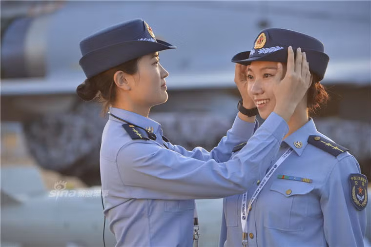 Hai nữ quân nhân đang giúp nhau chỉnh lại trang phục để duy trì hình ảnh nghiêm chỉnh và xinh đẹp trước mắt công chúng. Ảnh: Sina