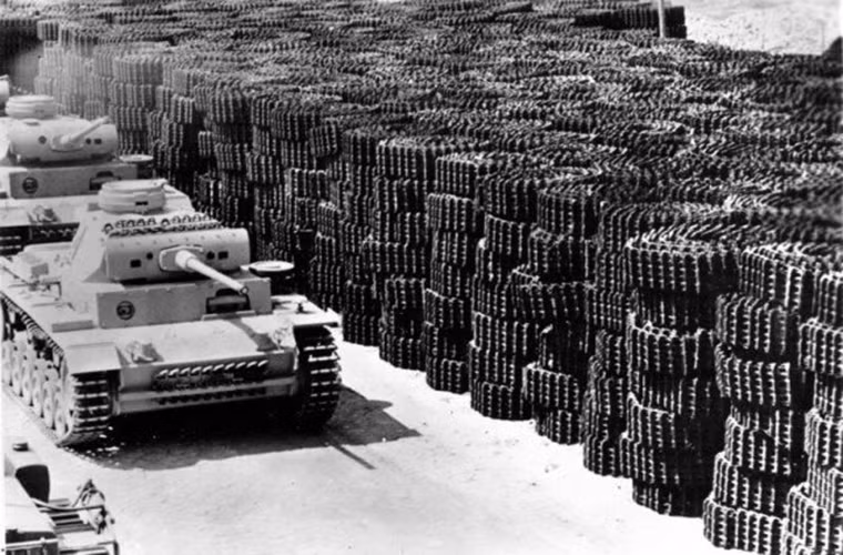 Hình ảnh xe tăng Panzer III của Đức di chuyển ra khỏi xưởng chế tạo sau khi được hoàn thiện. Bên cạnh nó là một núi bánh xích tải dành cho những chiếc xe tăng trong tương lai. Bức ảnh này được chụp vào năm 1942. Nguồn ảnh: War History.