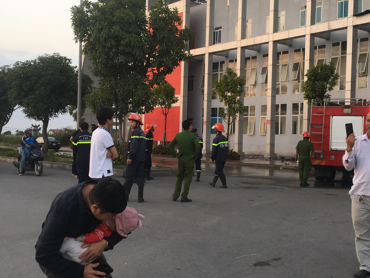 Một ông bố bế con vào lòng thời điểm lực lượng Cảnh sát PCCC đang khống chế ngọn lửa.