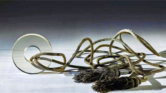 Trong quá trình làm việc xung quanh ngôi mộ cổ được cho là thuộc thời Nam Tống, cách đây 800 năm, chuyên gia phát hiện một vật thể phát sáng khi được ánh sáng chiếu vào, đó là một miếng thủy tinh hình tròn xỏ qua dây. Miếng thủy tinh này khiến các nhà khảo cổ bối rối vì tính hiện đại của nó.