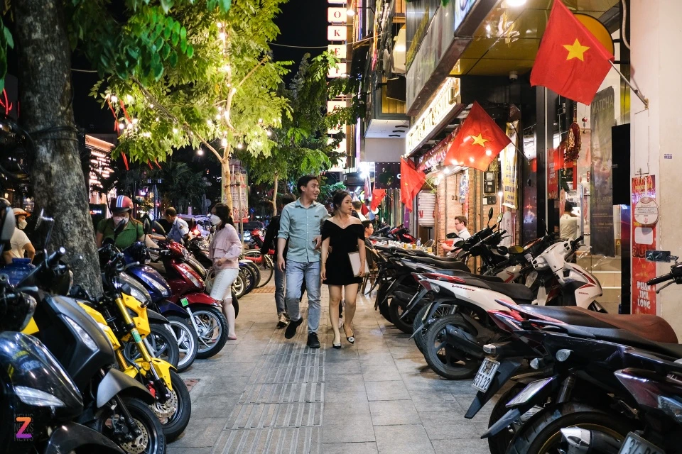 Từ khi trở thành phố ẩm thực, vỉa hè được tận dụng làm chỗ để xe. Hai hàng xe xếp ngay ngắn tạo thành lối đi thoáng đãng ở giữa thành cho thực khách. Các hàng quán treo cờ, treo đèn trang trí khiến không khí nơi đây trở nên sinh động.