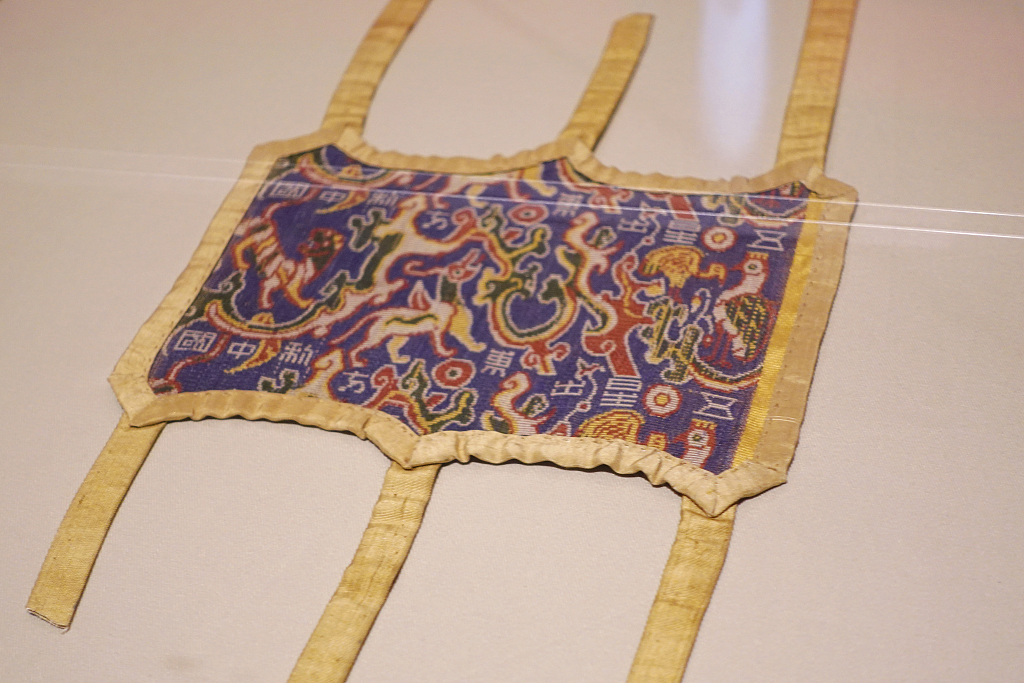 Tấm vải này thuộc về một ngôi mộ xa hoa và được xác định là băng tay, dùng để bảo vệ tay khi sử dụng cung tên.