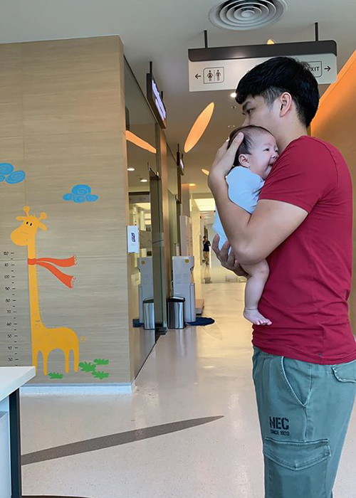Hình ảnh chồng trẻ của Lê Phương bồng con gái đi tiêm phòng.
