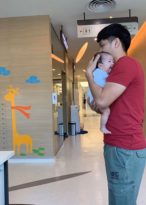 Hình ảnh chồng trẻ của Lê Phương bồng con gái đi tiêm phòng.