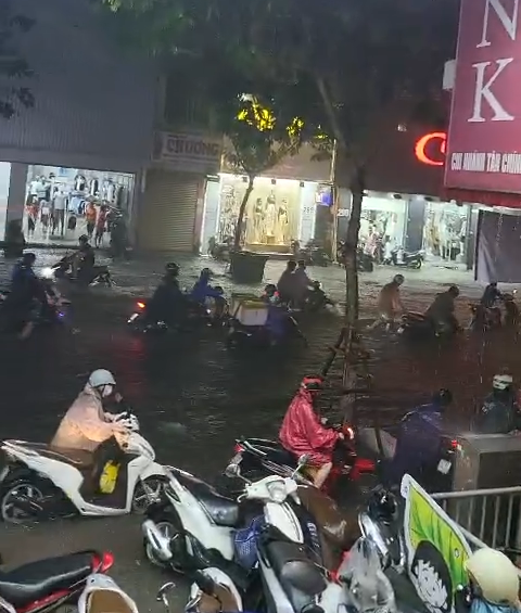 Nhiều người đành phải dắt xe lên vỉa hè chờ ngớt mưa, nước rút.