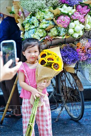 Em bé Hà Nội được mẹ chụp ảnh bên chiếc xe hoa rong trên đường Trúc Bạch giữa tiết trời Thu Hà Nội.