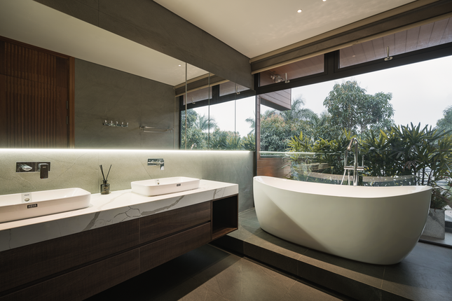 Phòng vệ sinh được trang bị đầy đủ với bồn tắm nằm và view kính lớn nhìn ra mặt tiền, cùng với hai chậu rửa mặt. Tất cả những tiện nghi này tạo nên một không gian sống thoải mái, giống như một resort thu nhỏ, mang lại sự hài lòng cho gia chủ. Bồn tắm nằm với view kính lớn nhìn ra mặt tiền, tạo cảm giác "chill", thư thái.