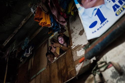 Người phụ nữ chụp ảnh hiện trường một vụ đấu súng của băng đảng ma túy tại khu ổ chuột ở thủ đô Manila hôm 23/8.