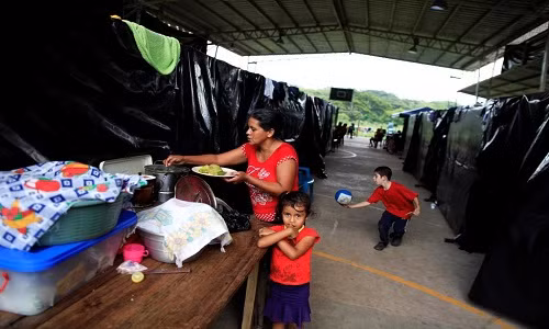 Người phụ nữ đang chuẩn bị đồ ăn cho các con của cô tại khu trại ở thị trấn Caluco, El Salvador, hôm 27/9.