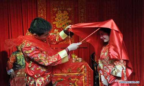 Đám cưới đặc biệt theo phong tục truyền thống diễn ra trước sự chứng kiến và chúc phúc của gia đình và các khách mời. Ảnh: Chú rể Shen Kai vén chiếc khăn đỏ che mặt của cô dâu.