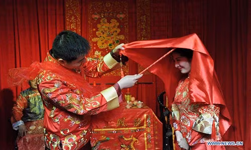 Đám cưới đặc biệt theo phong tục truyền thống diễn ra trước sự chứng kiến và chúc phúc của gia đình và các khách mời. Ảnh: Chú rể Shen Kai vén chiếc khăn đỏ che mặt của cô dâu.