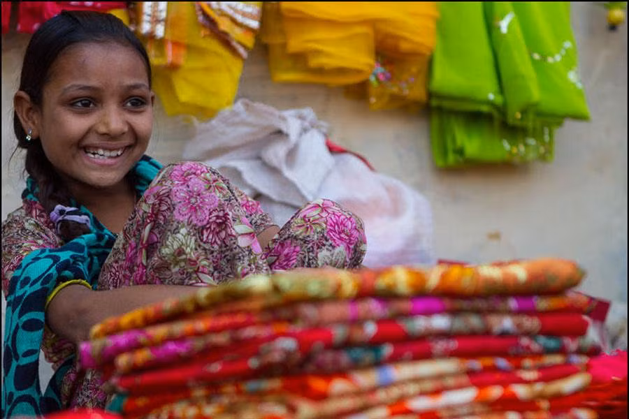 Bé gái cười tươi bán đồ tại khu chợ.