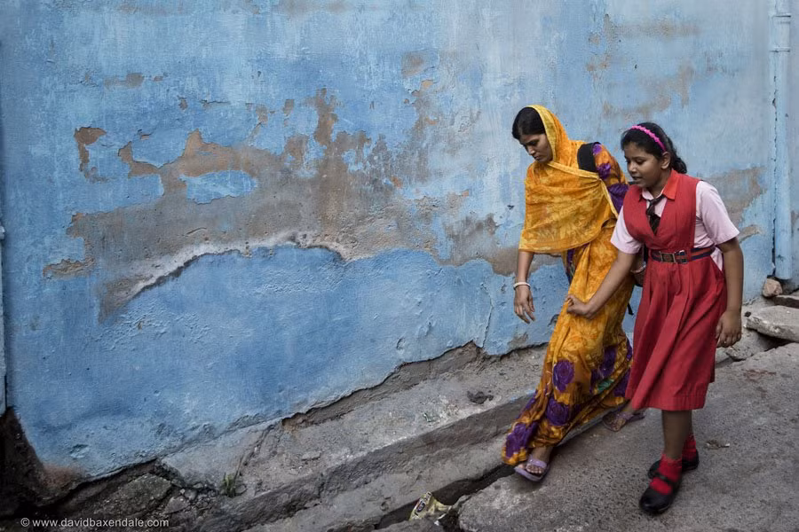 Một phụ nữ đưa con gái về nhà sau khi tan trường ở thành phố xanh của Ấn Độ.